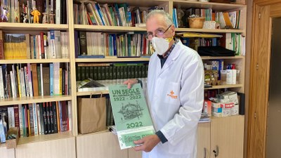 El president d'Amics de Cerdanya, Joan Muntané, mostrant l'edició 2022 del Calendari Cerdà, dedicat al centenari de l'arribada del ferrocarril a la comarca (Foto: ACN)