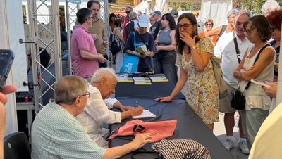 Artur Blasco, acompanyat de Ferran Riera i Jordi Martí Fabra, signa un exemplar del llibre 'Tornar al poble el que és del poble' (Foto: Sílvia Blasco)