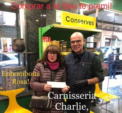Rosa Ballesteros recull, a la botiga de Carnisseria Charlie, el val de 100 euros que ha guanyat en el concurs 'Comprar a la Seu té premi'