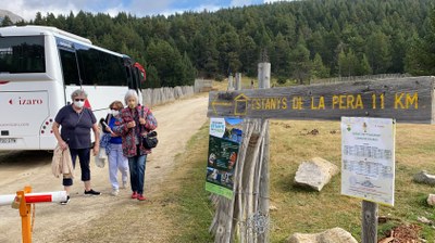 Tres visitants, al costat del bus llançadora per accedir als Estanys de la Pera (Foto: ACN)