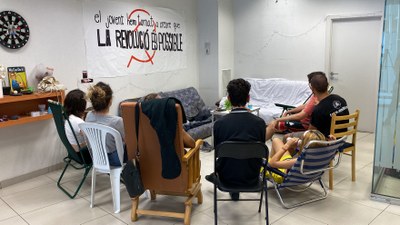 Diversos joves, d'esquena, reunits a l'interior d'un local de la Seu d'Urgell que ha estat ocupat per convertir-lo en casal (Foto: ACN)