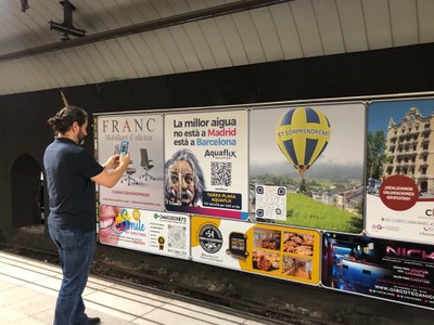 El regidor de Promoció Econòmica de la Seu, Jordi Mas Ortega, enfront del cartell promocional de la ciutat instal·lat al Metro de Barcelona