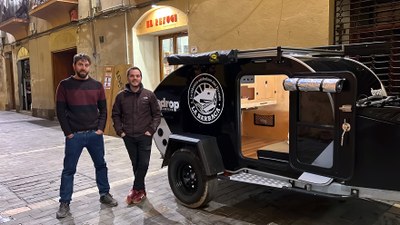 Pol Maese i Miquel Albero, socis treballadors de la cooperativa El Refugi, al costat de la nova caravana de llibres anomenada La Barraca, aparcada davant de la llibreria del carrer Canonges de la Seu d'Urgell (Foto: ACN)